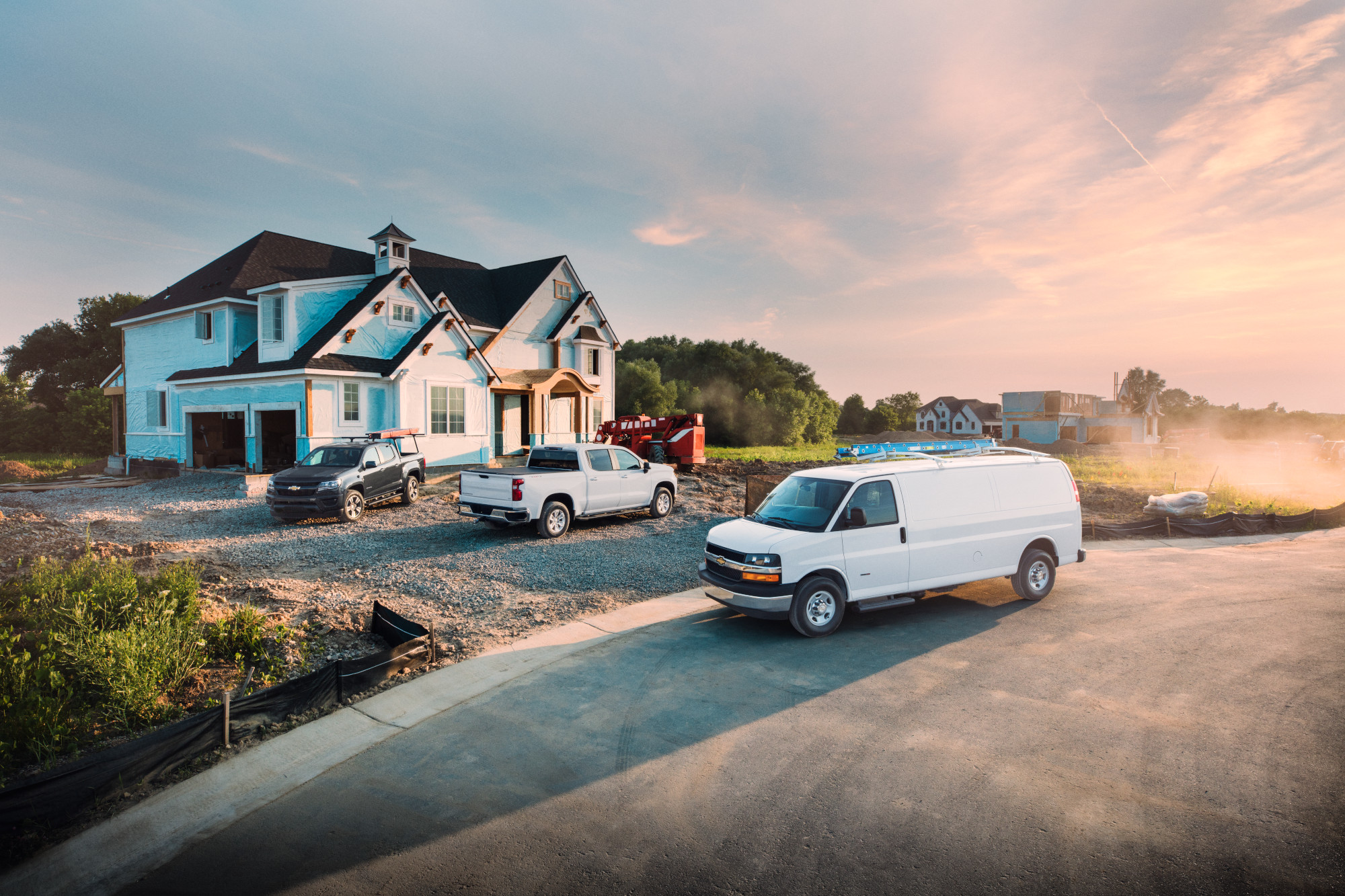 White Cargo van and two work trucks on a construction site