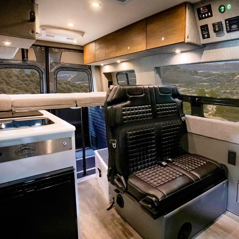 The interior of a Storyteller Overland MODE van, featuring a bed, kitchenette, and comfortable seating, emphasizing the spacious and functional living area for vanlife.