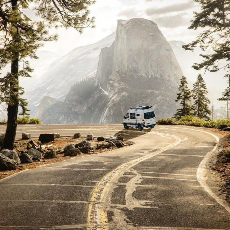 A Storyteller Overland van on a winding mountain road with a large peak in the background, suggesting adventure and scenic travel from Irondale, AL.
