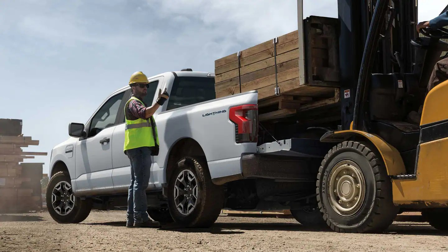 Ford F-150 Lightning Pro hauling construction materials at a job site.