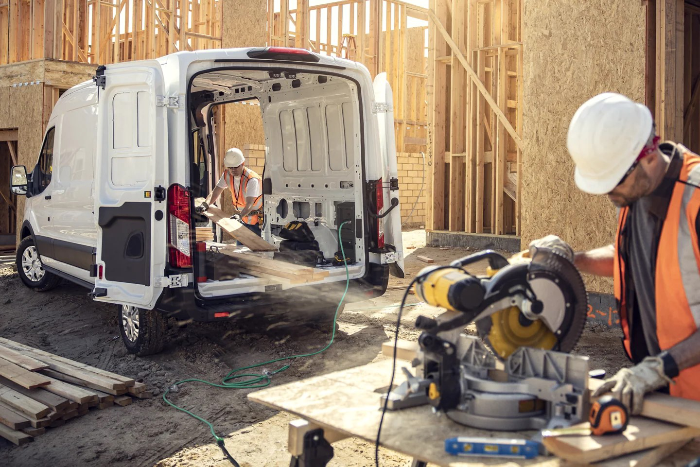 A Ford E-Transit van parked at a construction site, delivering materials.