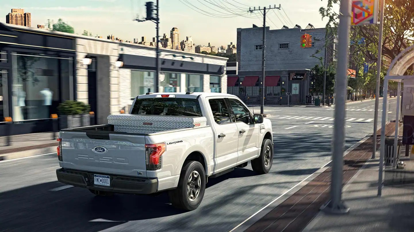 Ford F-150 Lightning Pro driving through a bustling city center in Raleigh, NC.