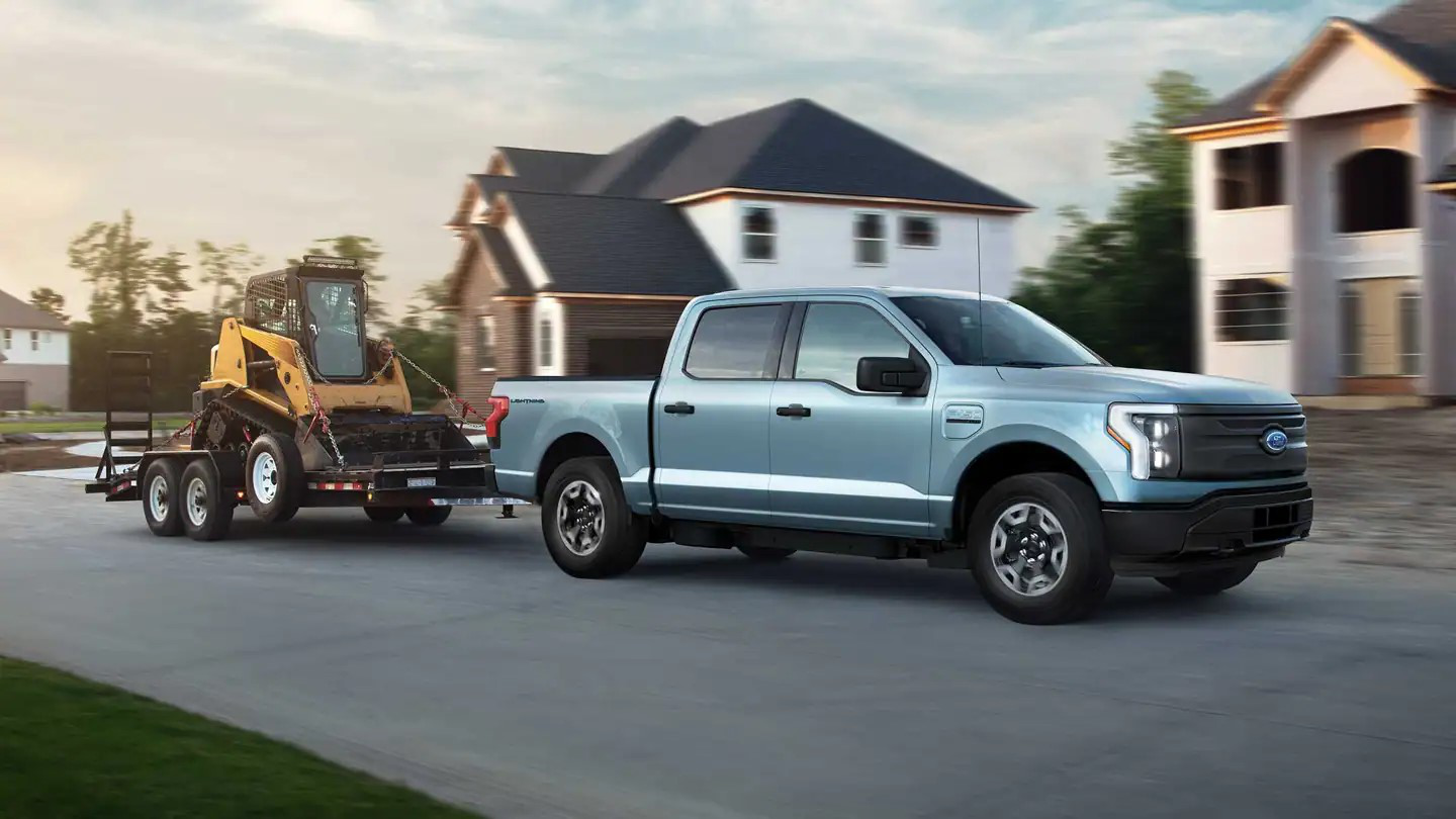 Ford F-150 Lightning Pro towing a trailer with construction equipment through a neighborhood in Raleigh, NC.