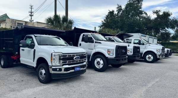 A lineup of white Ford commercial dump truck vehicles for sale at Bill Currie Ford in Tampa, FL.