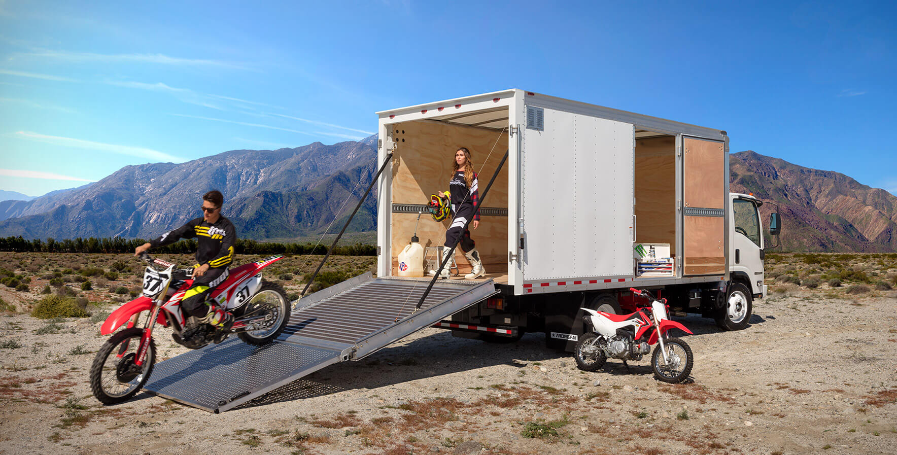 A team of BMX bikers rolling out of a Morgan ProScape box truck onto a dirt track in Wake Forest, NC.