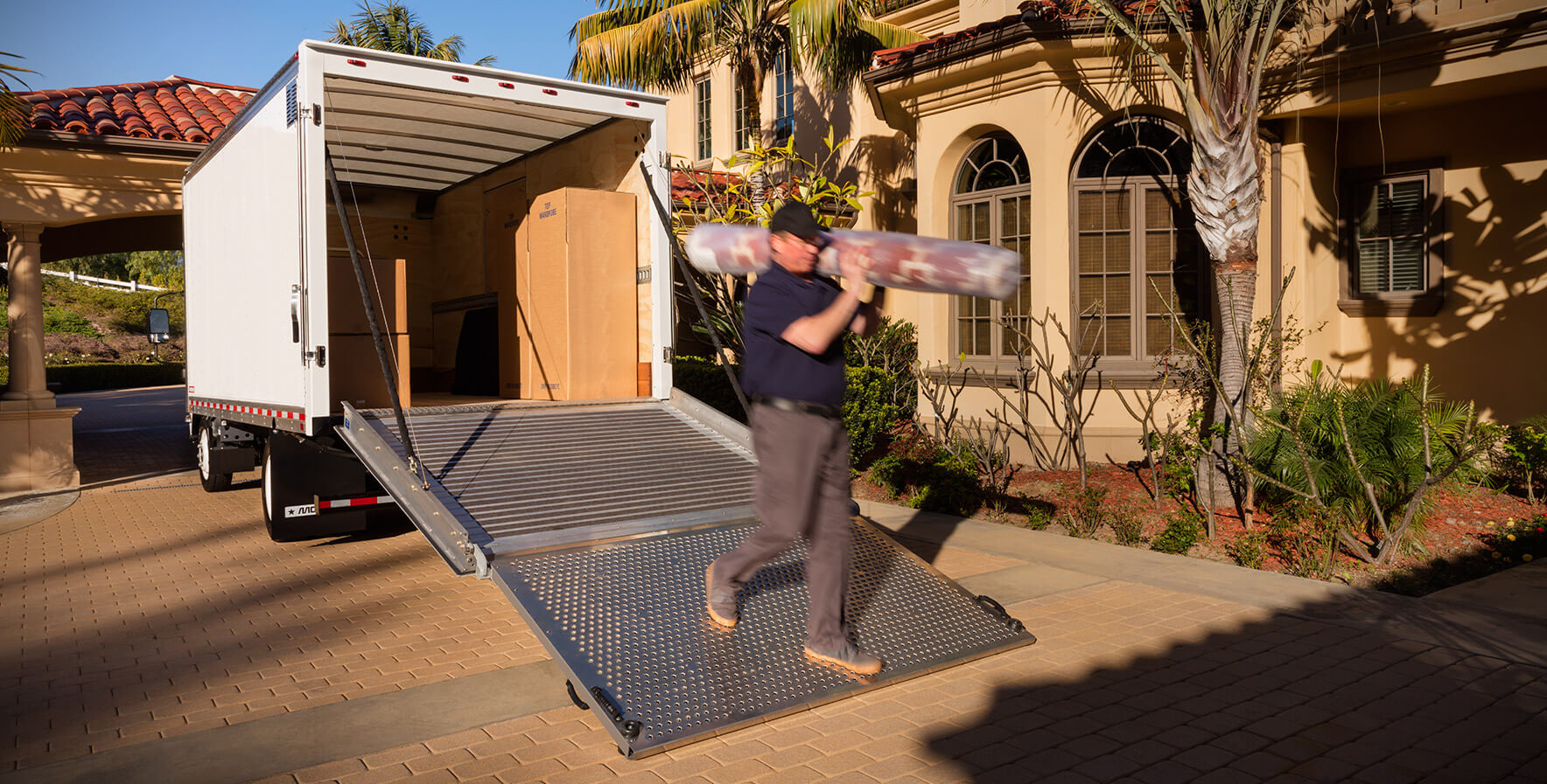 A mover unloading furniture from a Morgan ProScape box truck equipped with a liftgate.